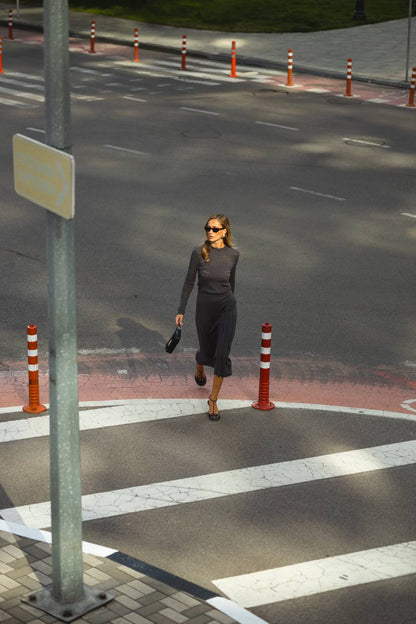 Woman walking on a crosswalk with traffic cones and a street sign in the background