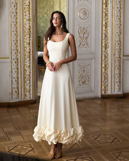 Woman in a white dress standing in an ornate room with decorative walls.