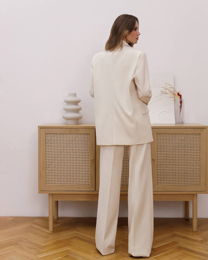 Woman in a beige suit standing in front of a wooden cabinet with wicker doors.