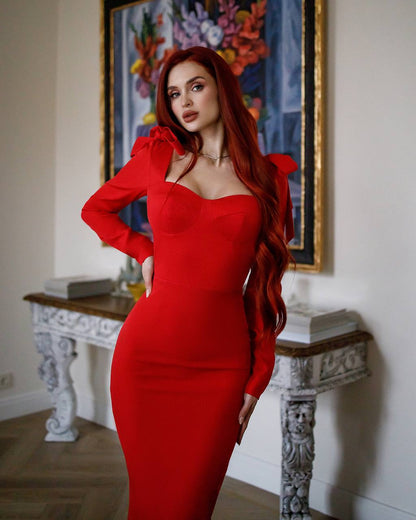 Woman in a red dress posing indoors with a decorative painting in the background