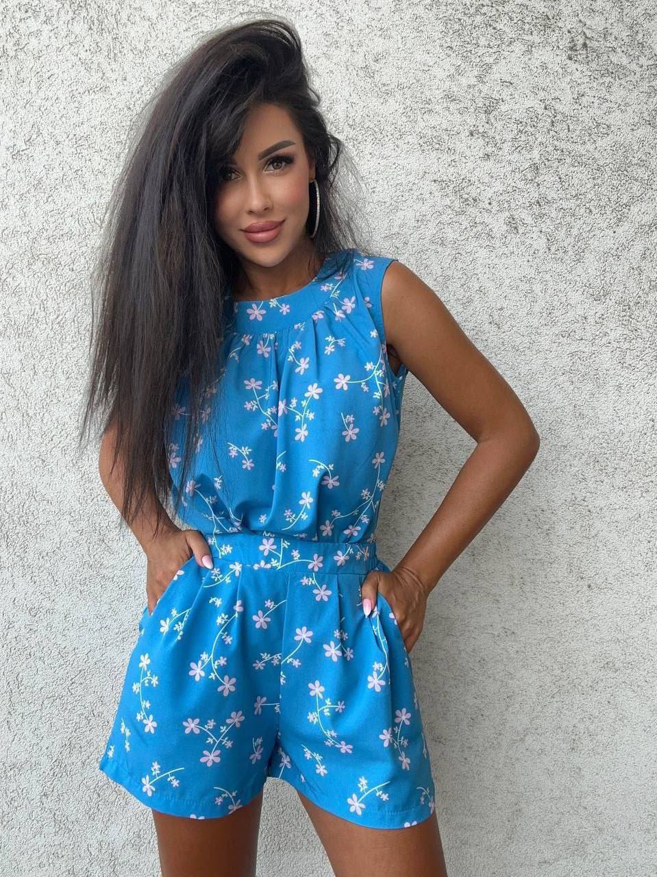 Woman wearing a blue floral romper against a gray background