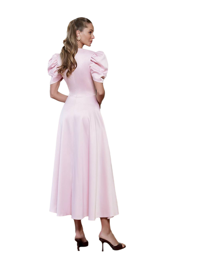 Woman wearing a pink dress with puffed sleeves on a white background