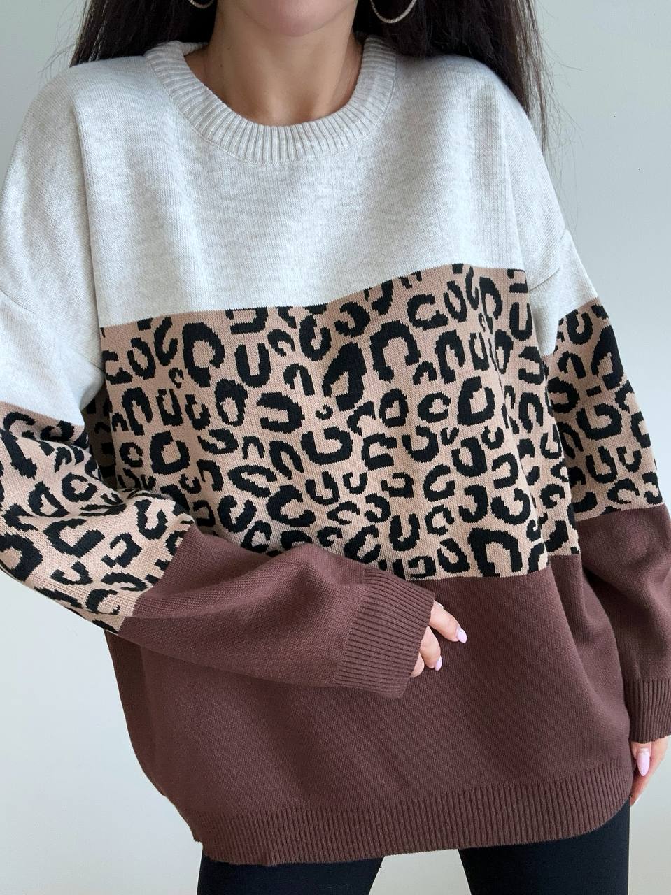 Sweater with leopard print sleeves and brown bottom section on a plain background