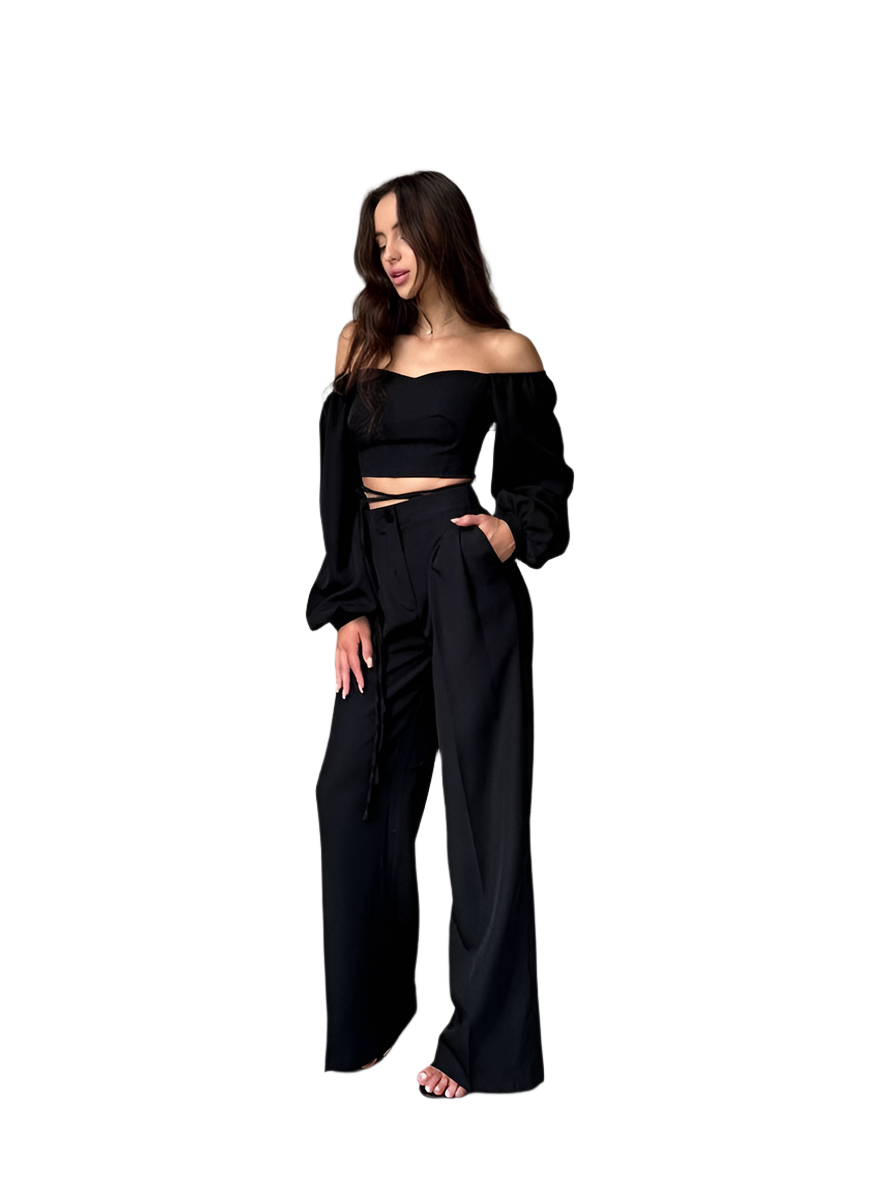 Woman wearing a black off-shoulder top and wide-leg pants on a white background