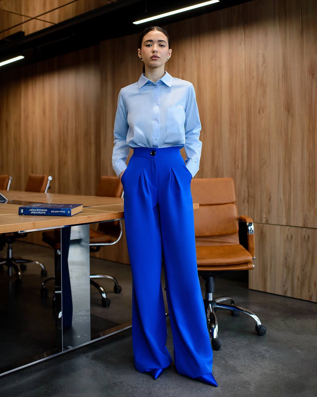 Person wearing a light blue shirt and bright blue pants in an office setting