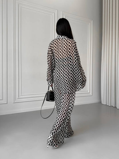 Person wearing a patterned outfit standing in a room with white walls and gray floor.
