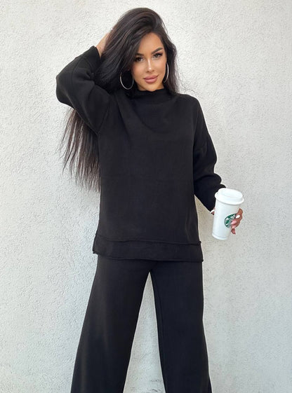 Woman in black outfit holding a Starbucks cup against a light gray background