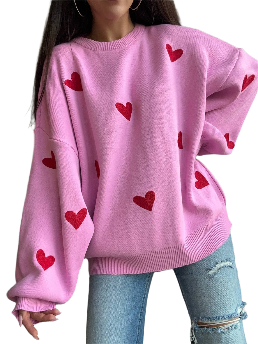 Pink sweater with red heart patterns worn by a person on a white background