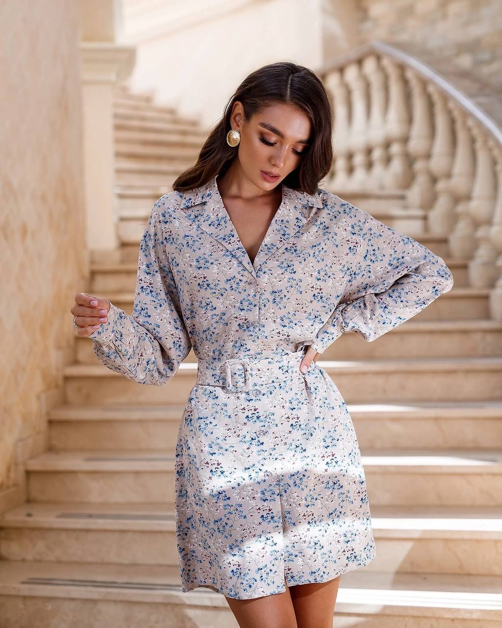 Woman wearing a floral dress standing on stone steps.