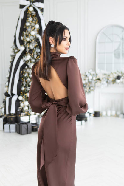 Woman in a brown dress standing in a decorated room with Christmas trees.