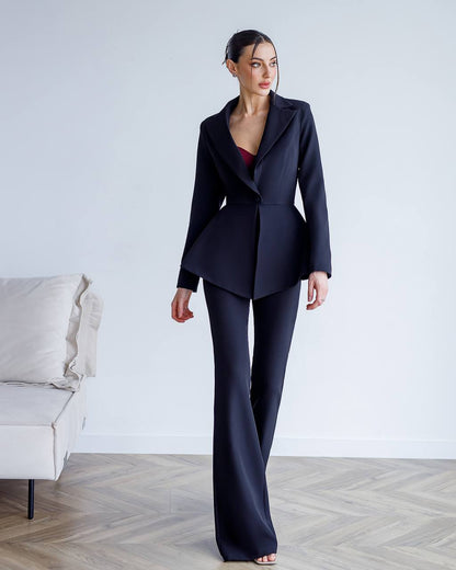 Woman wearing a dark blue suit standing in a minimalistic room with a white couch.