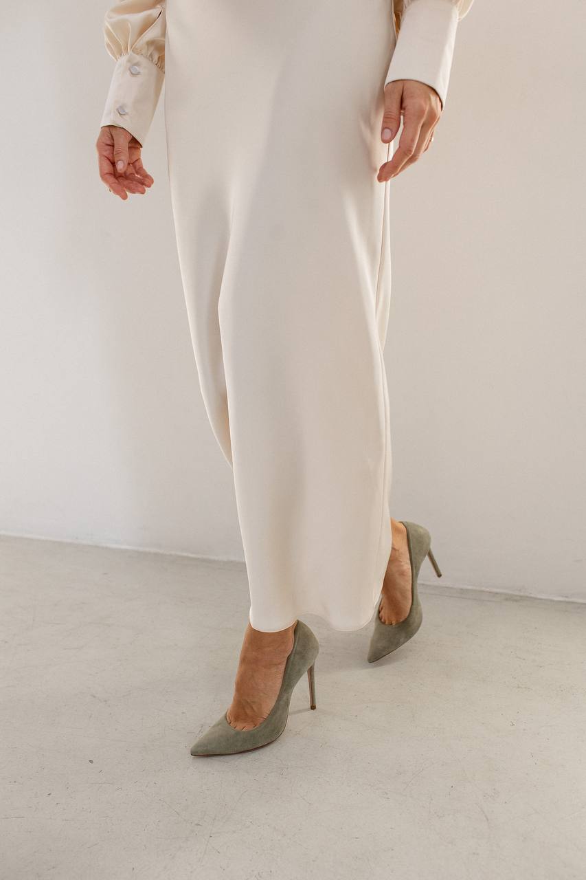 Person wearing white pants and gray high-heeled shoes on a plain background