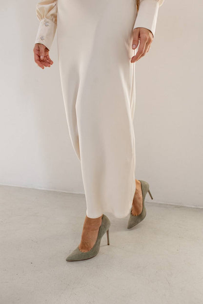 Person wearing white pants and gray high-heeled shoes on a plain background