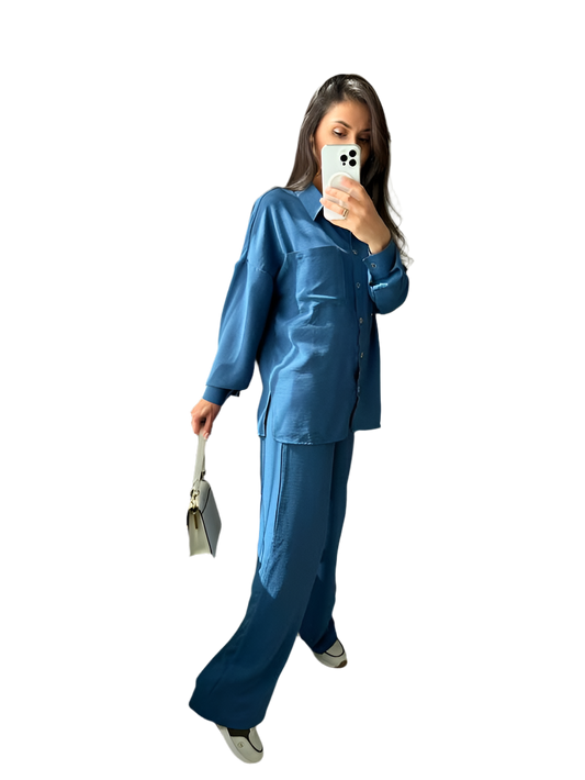 Person wearing a blue outfit taking a mirror selfie on a white background