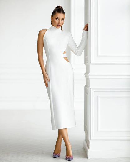 Woman wearing a white dress standing against a white wall.