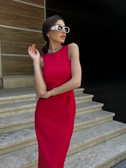 Woman in a red dress standing on steps wearing sunglasses.