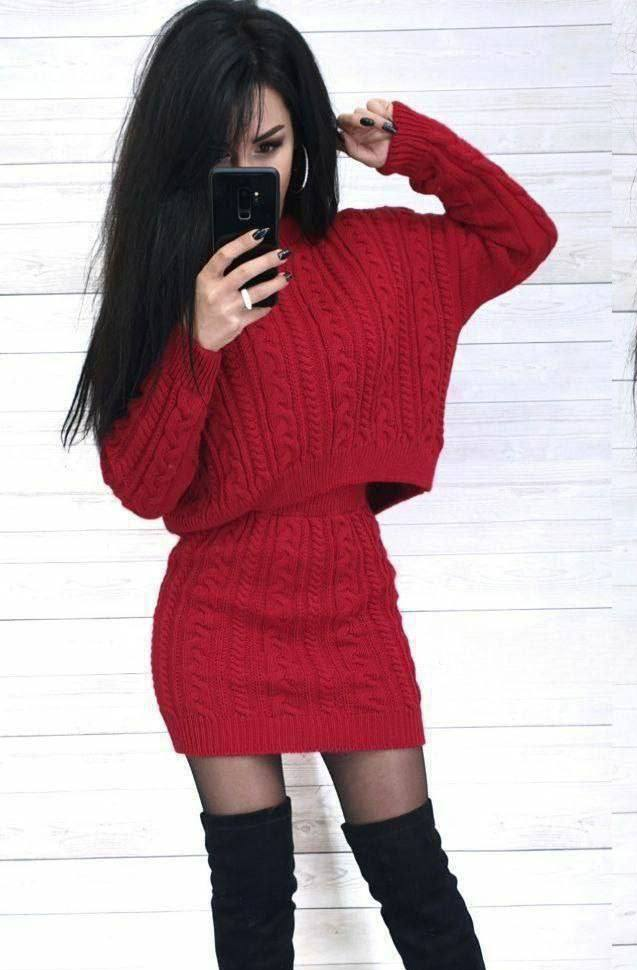 Person wearing a red sweater dress with black knee-high boots against a white wooden background