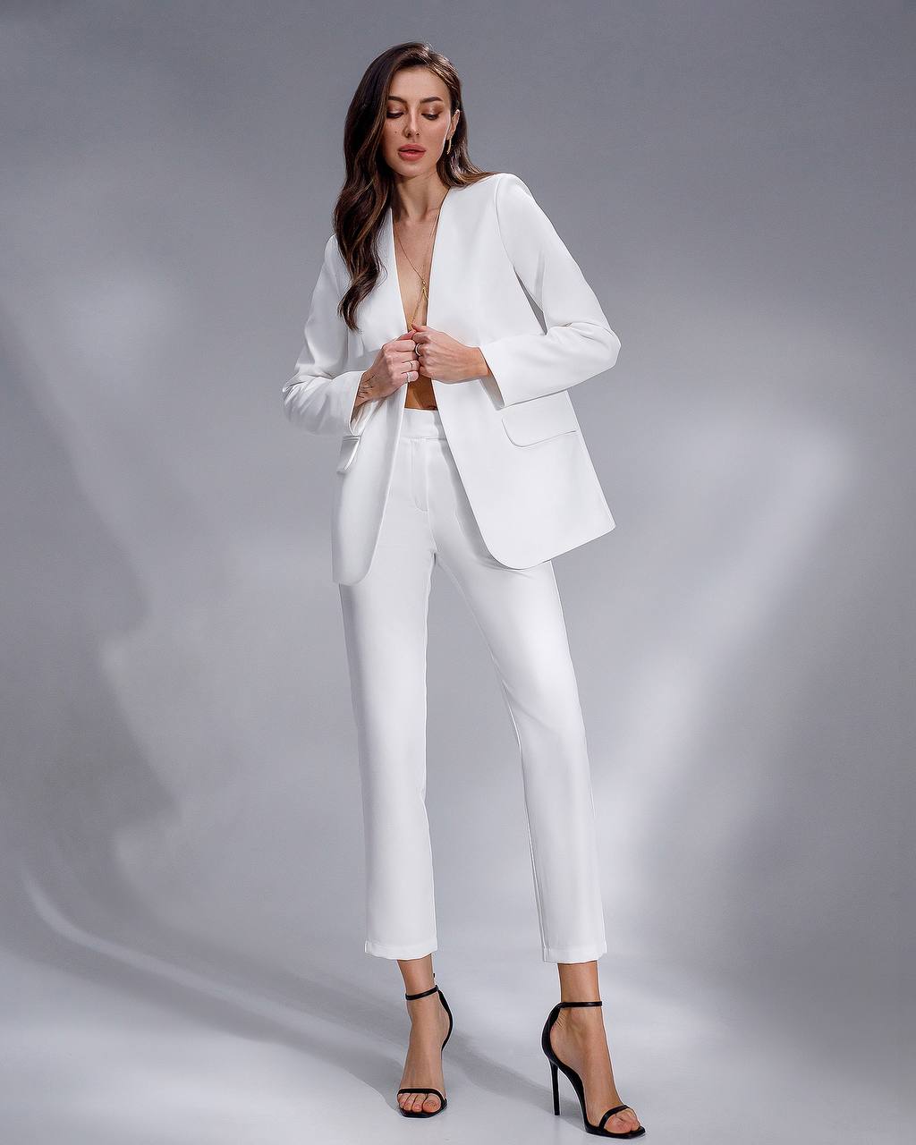 Woman wearing a white suit on a gray background