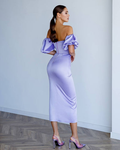 Woman wearing a lavender off-shoulder dress with puffed sleeves in an indoor setting.