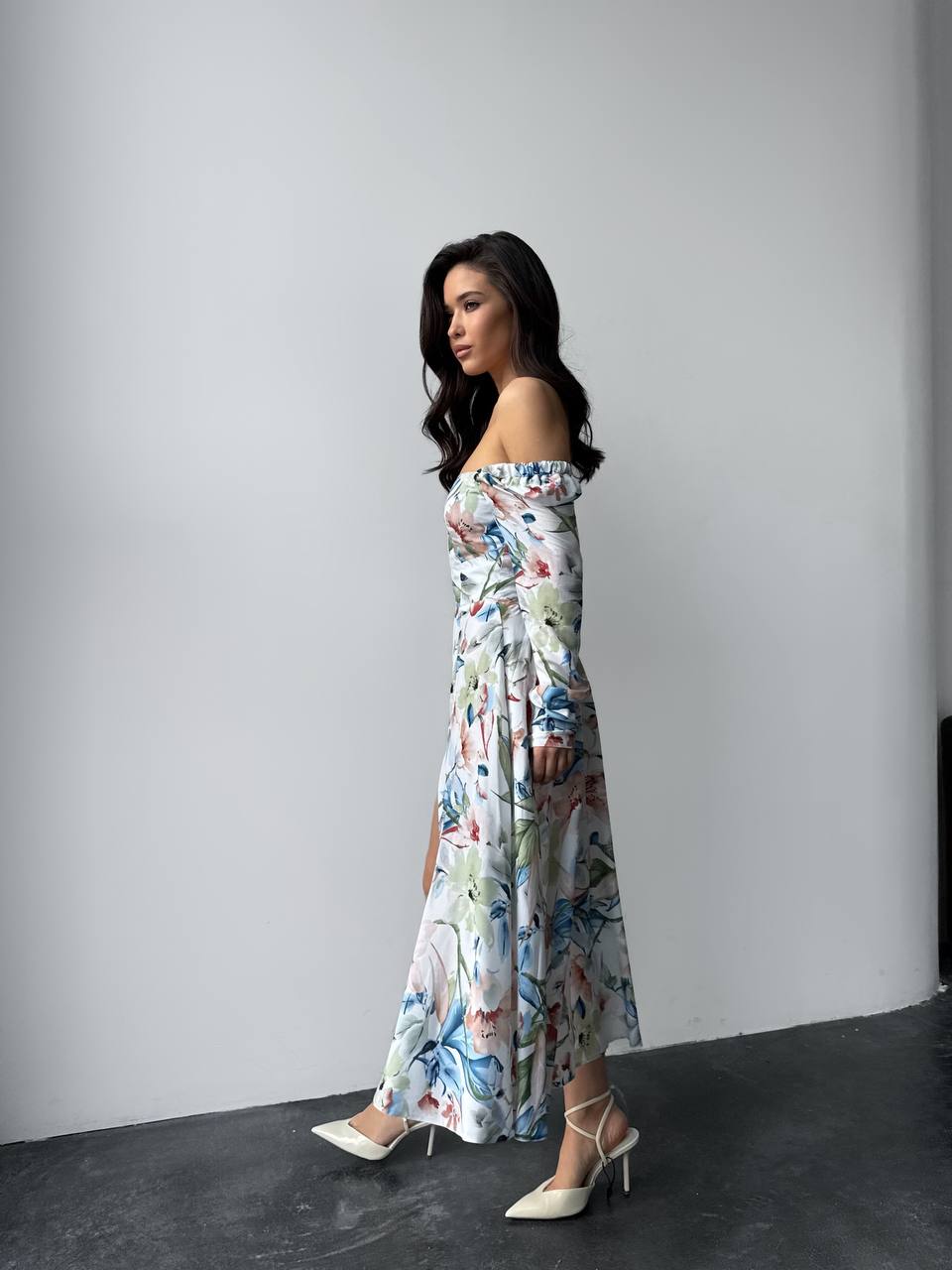 Woman wearing a floral off-shoulder dress against a plain background