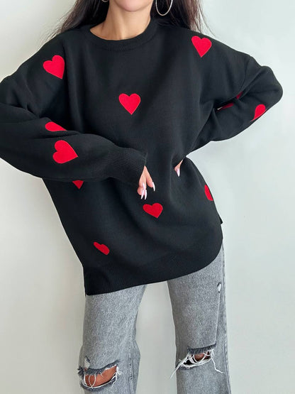 Person wearing a black sweatshirt with red heart patterns on a plain background
