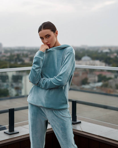 Person wearing a blue tracksuit on a balcony with a cityscape background