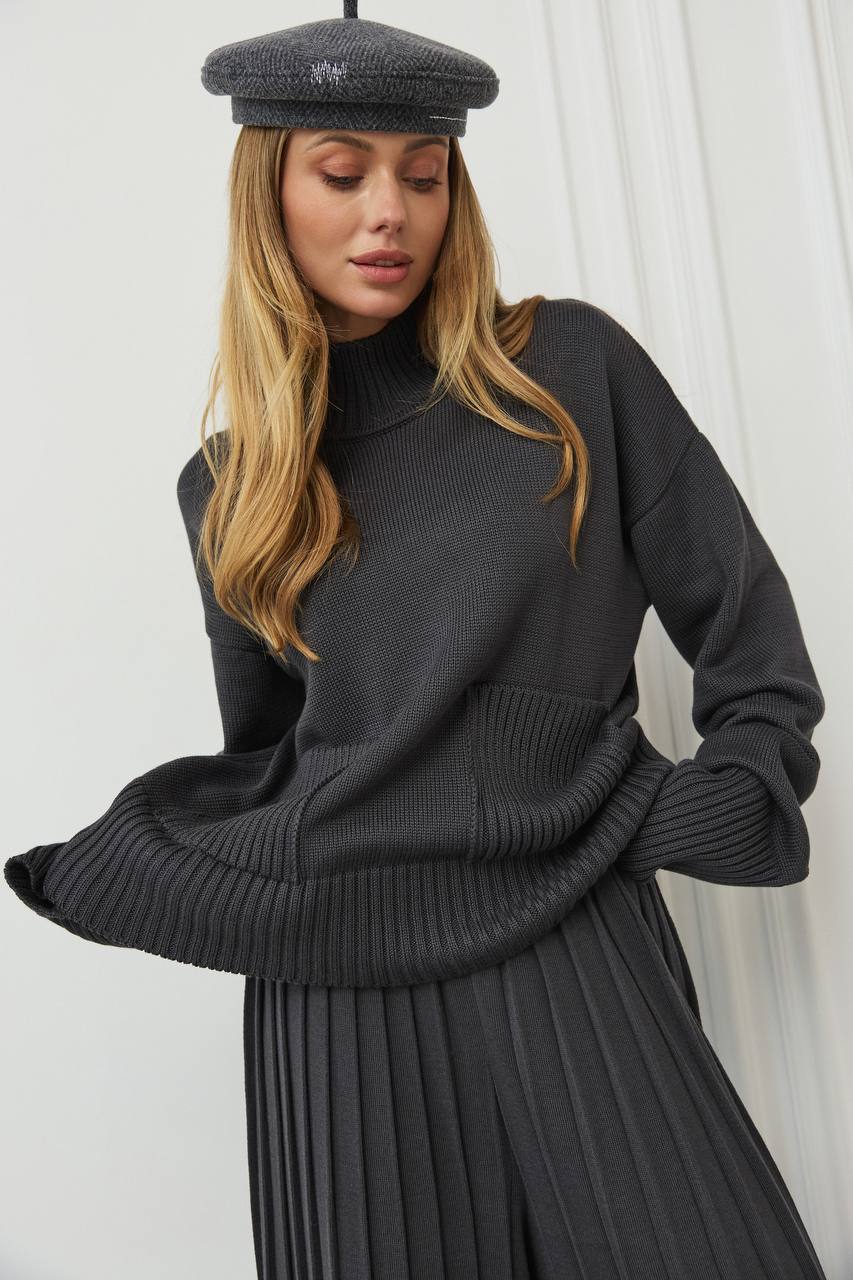 Woman wearing a dark gray sweater and beret against a white background