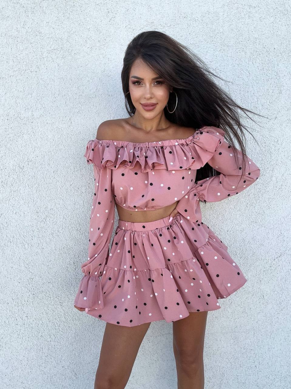 Woman wearing a pink polka dot dress against a light background