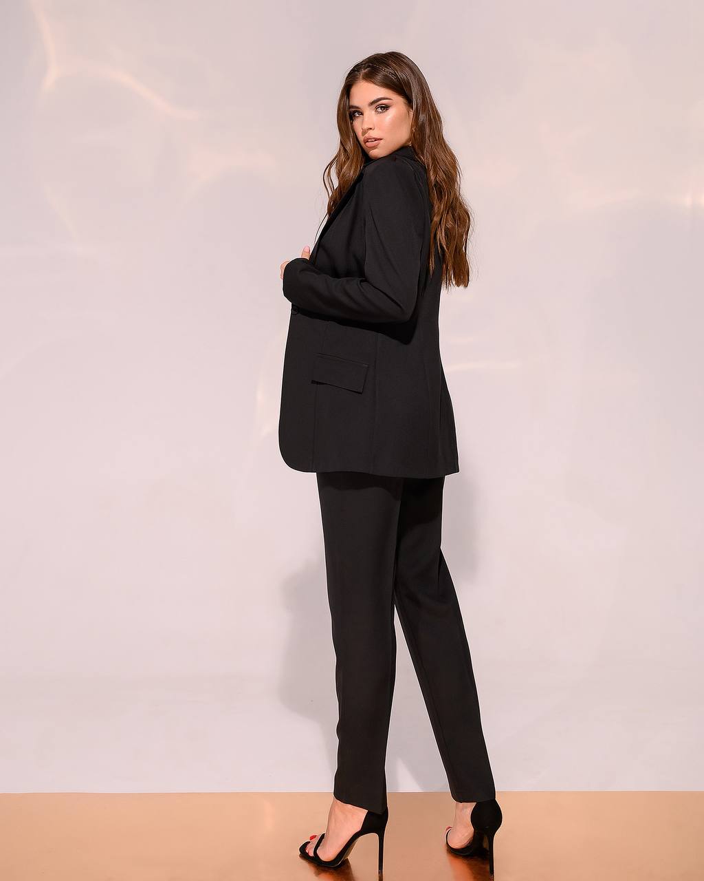 Woman wearing a black suit against a plain background