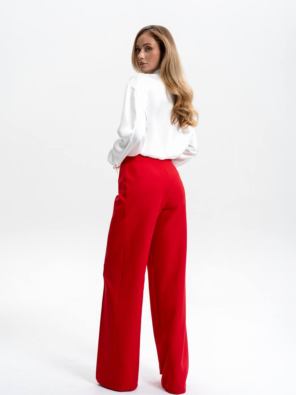 Woman wearing a white blouse and red pants on a white background