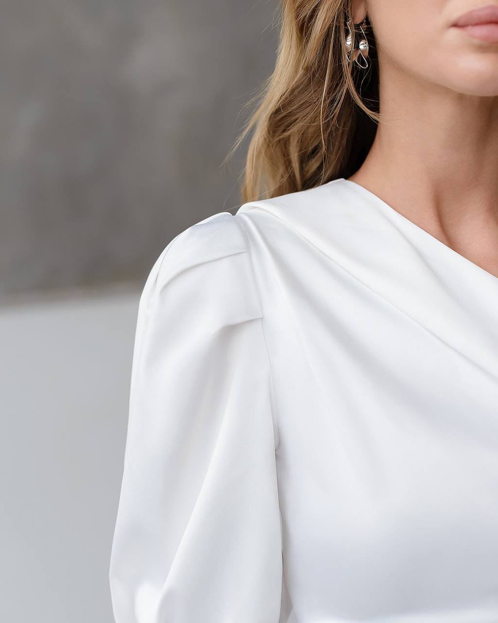 Close-up of a person wearing a white long-sleeve top with a blurred background