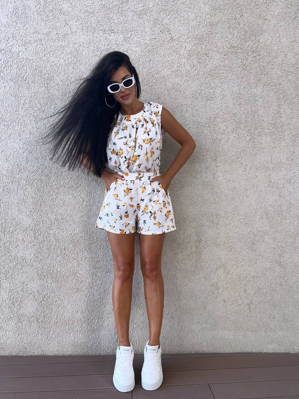 Woman in a floral outfit standing against a plain wall