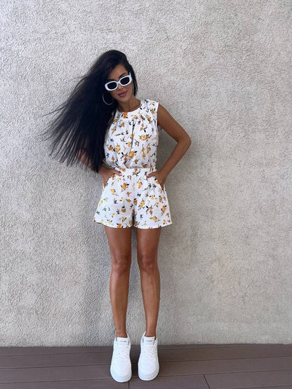 Woman in a floral outfit standing against a plain wall