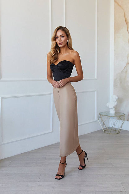 Woman wearing a black strapless top and beige pencil skirt in an elegant room.