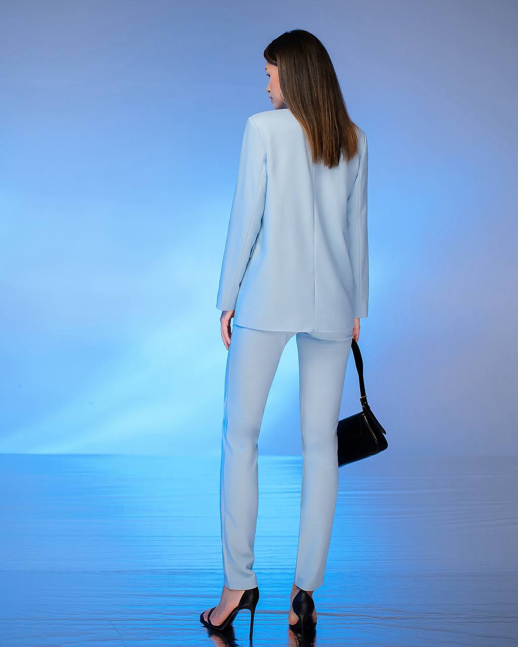 Woman in a light gray suit standing against a gradient blue background