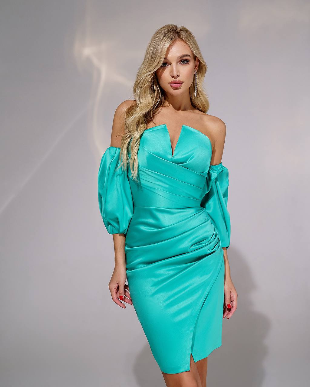 Woman wearing a turquoise dress against a plain background