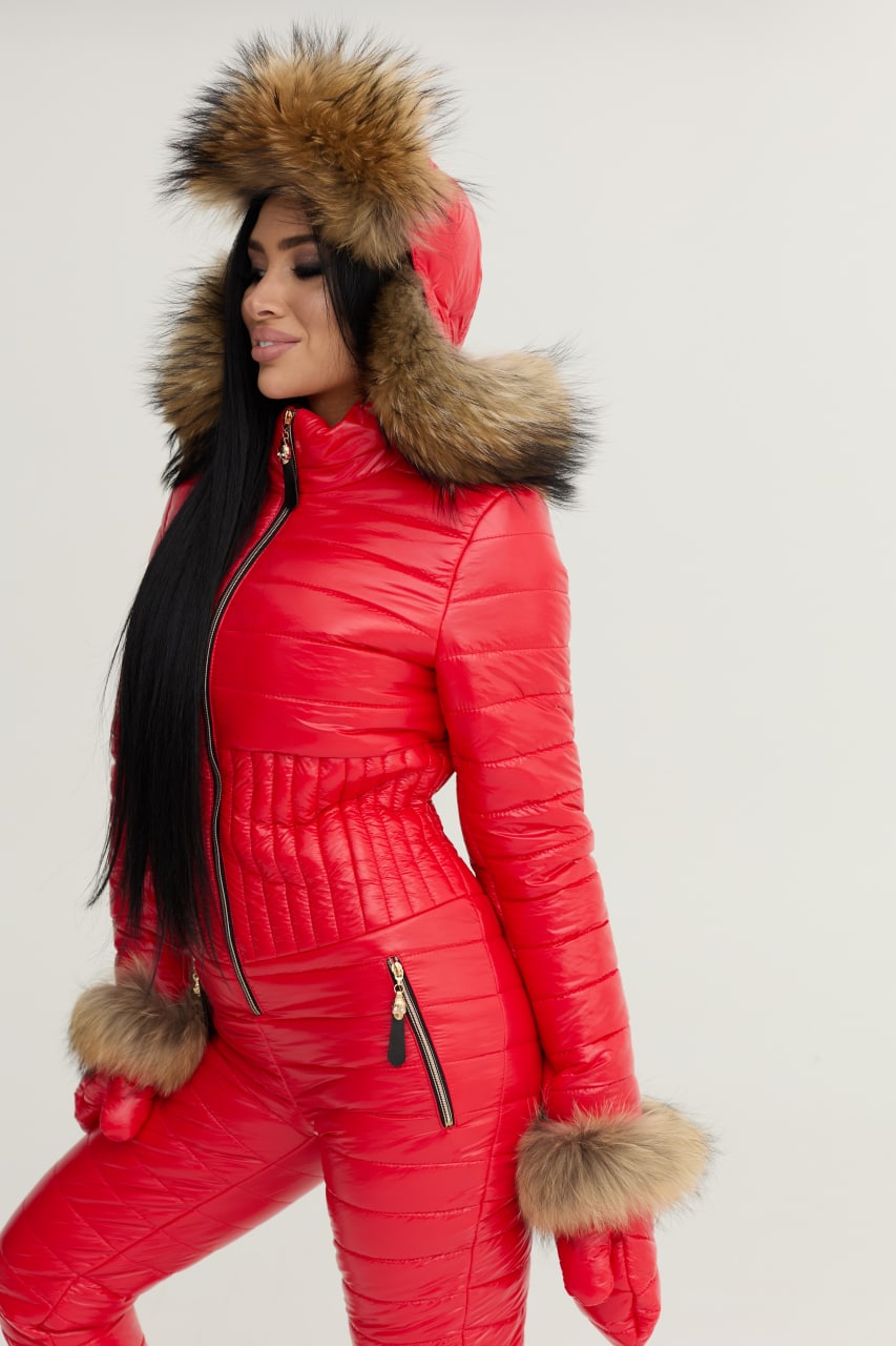 Person wearing a red puffer suit with fur trim on a plain background