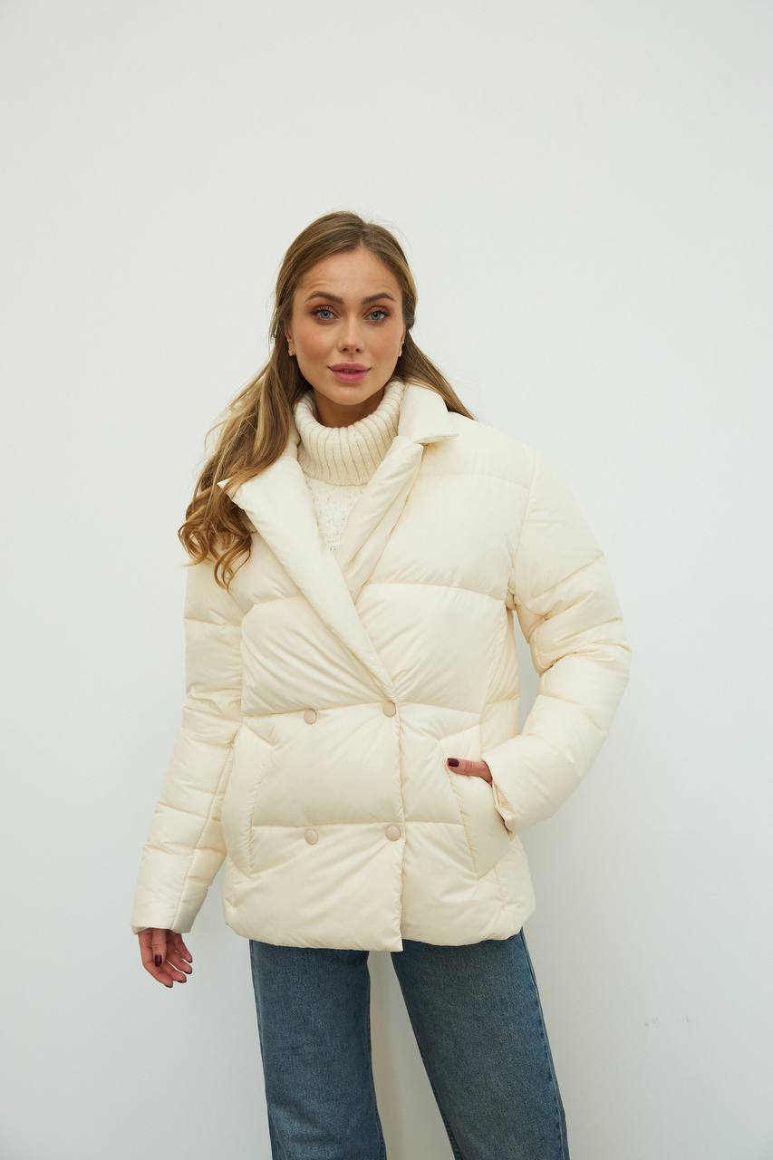 Woman wearing a white puffer jacket against a plain background