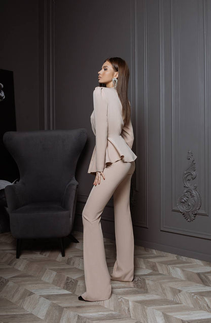 Woman in a beige outfit standing in an elegant room with gray walls and a patterned floor.