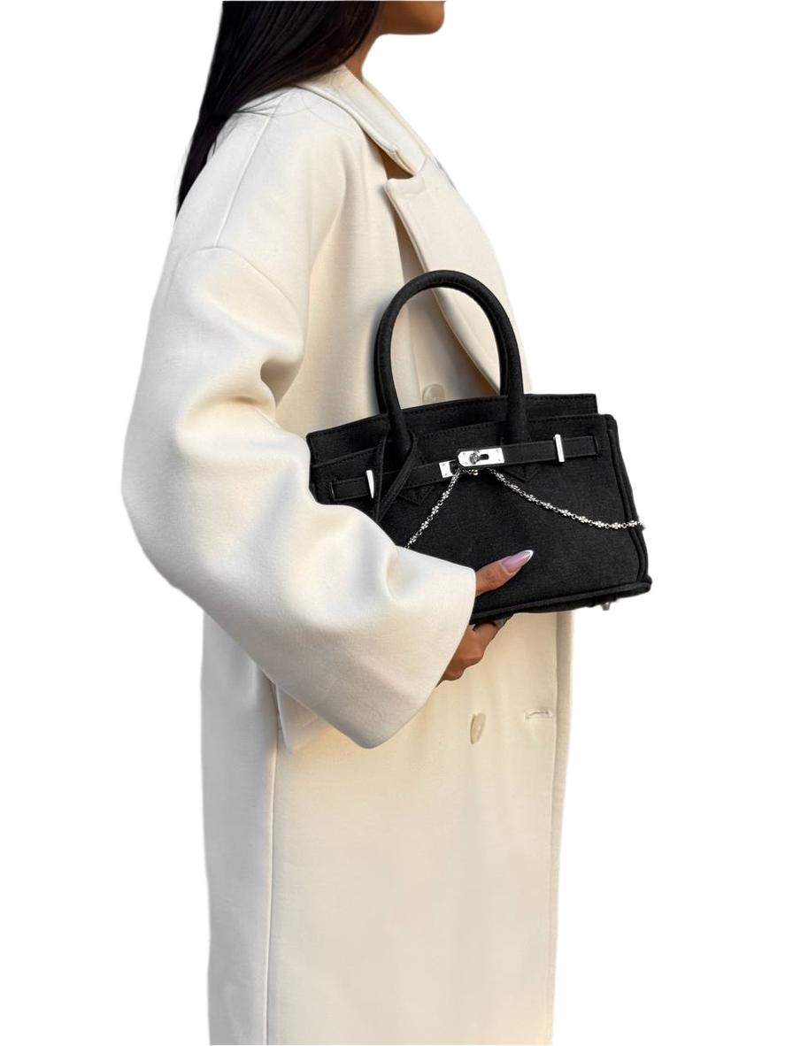 Person holding a black handbag with a white background