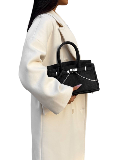Person holding a black handbag with a white background