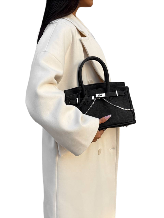 Person holding a black handbag with a white background