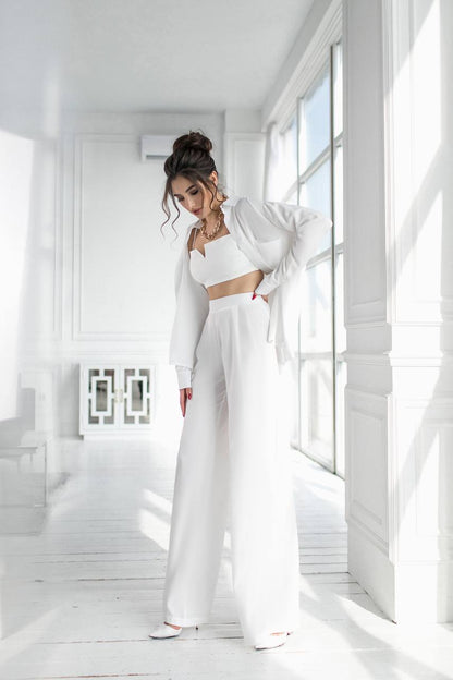 Woman in a white outfit standing in a bright, minimalistic room.