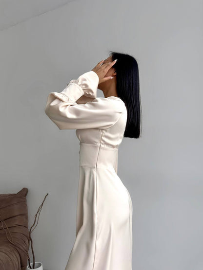 Person wearing a long white dress against a plain background