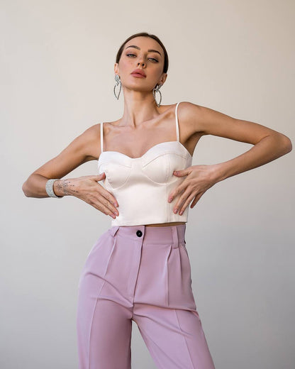 Woman wearing a white top and pink pants against a plain background
