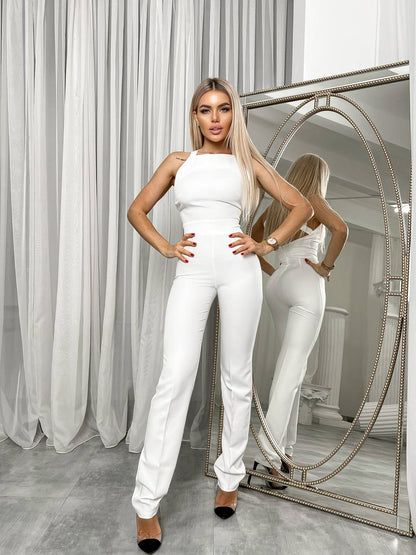 Woman in a white outfit posing in front of a mirror in a stylish room.