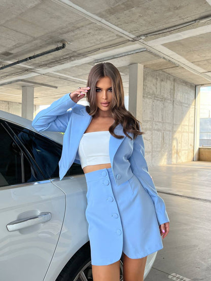 Woman in a light blue suit standing next to a car in an indoor setting