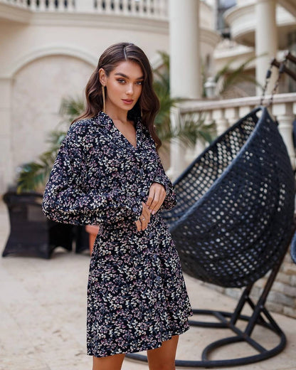 Woman in a floral dress standing in an outdoor setting with a hanging chair.