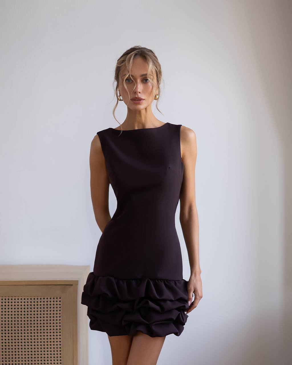 Woman wearing a black dress with ruffled hem against a plain background