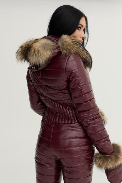 Person wearing a maroon puffer jacket with fur trim on a white background